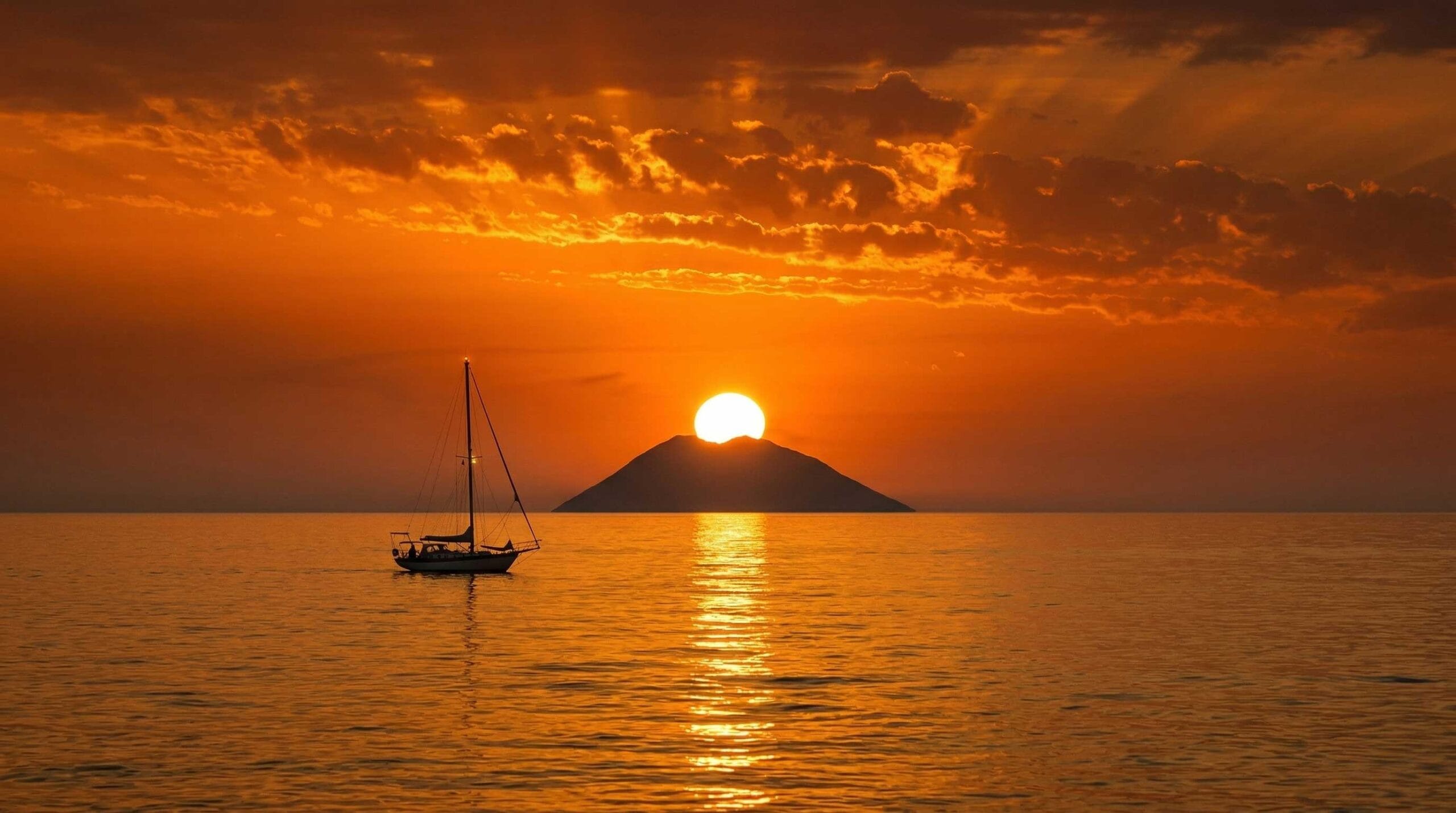 Tramonto sul cratere dello Stromboli visto dalla Costa degli Dei con il cielo tinto di arancio e rosso sul mare Tirreno